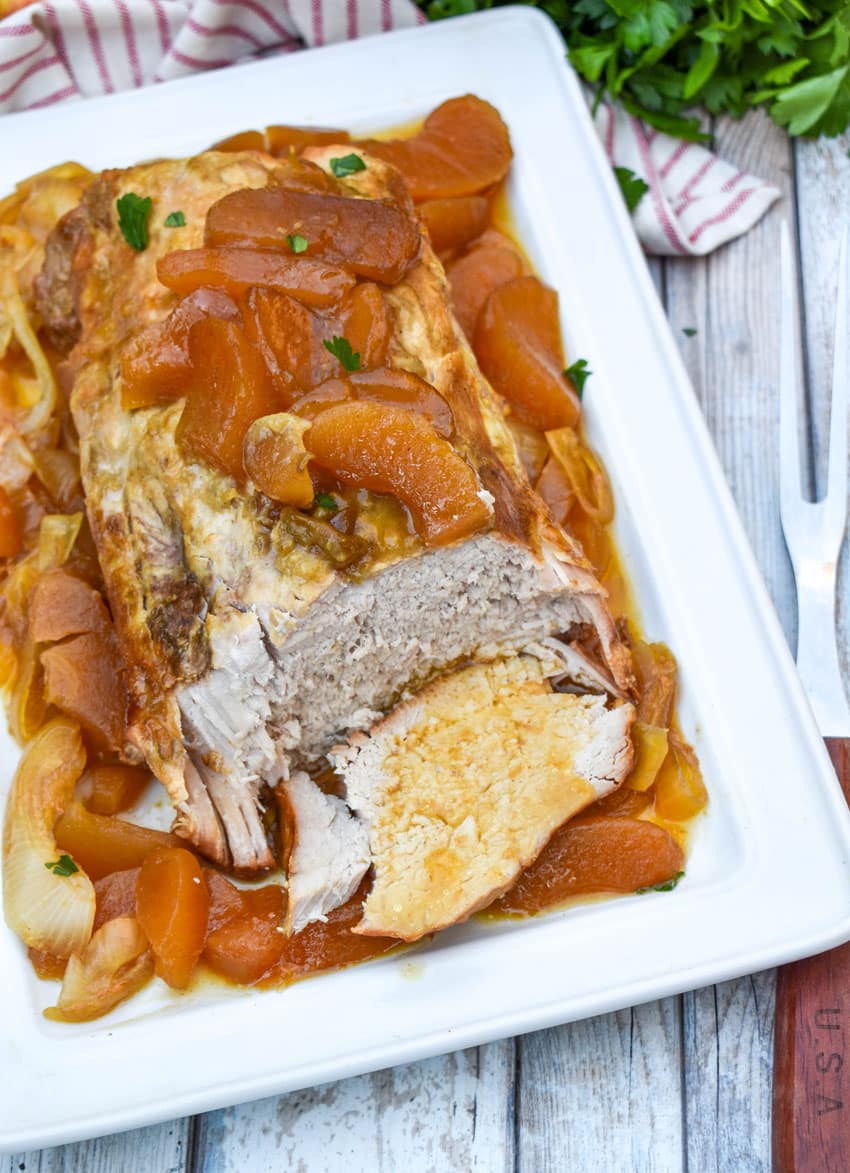 a slow cooked apple pie pork loin on a white serving platter