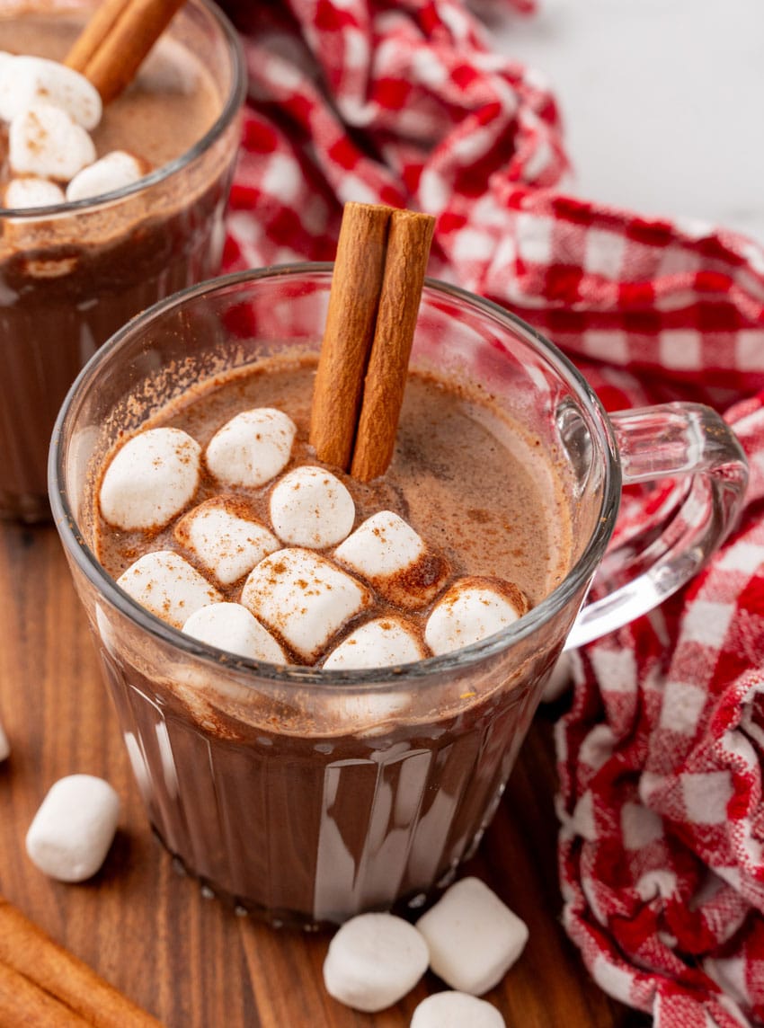 mexican hot chocolate studded with mini marshmallows and a cinnamon stick in a small glass jar