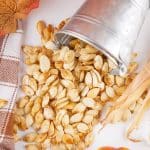 homemade roasted pumpkin seeds spilling out of a small metal pail onto a white countertop