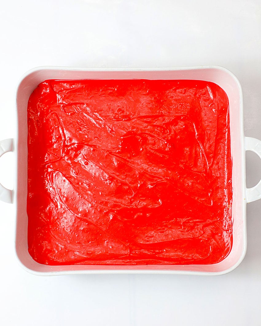 red cheesecake filling in an even layer in a white square baking dish