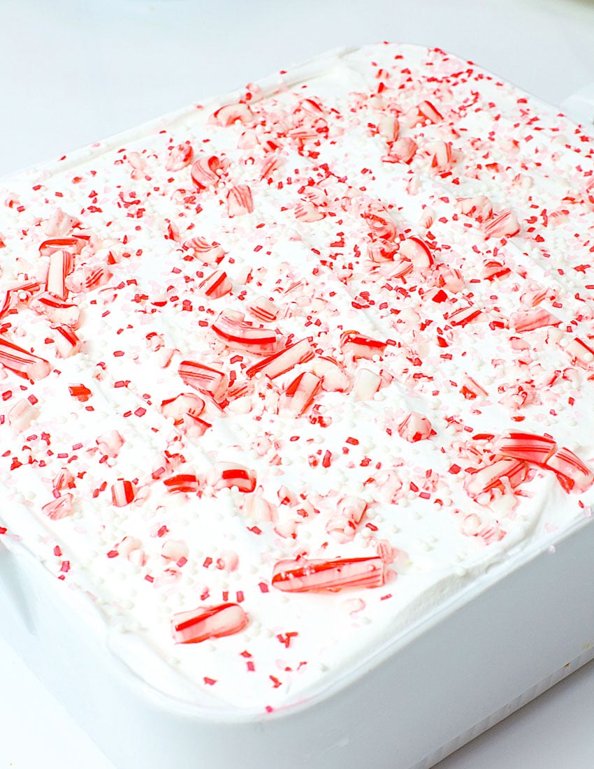 a candy cane lush dessert topped with peppermint candy pieces in a white square baking dish