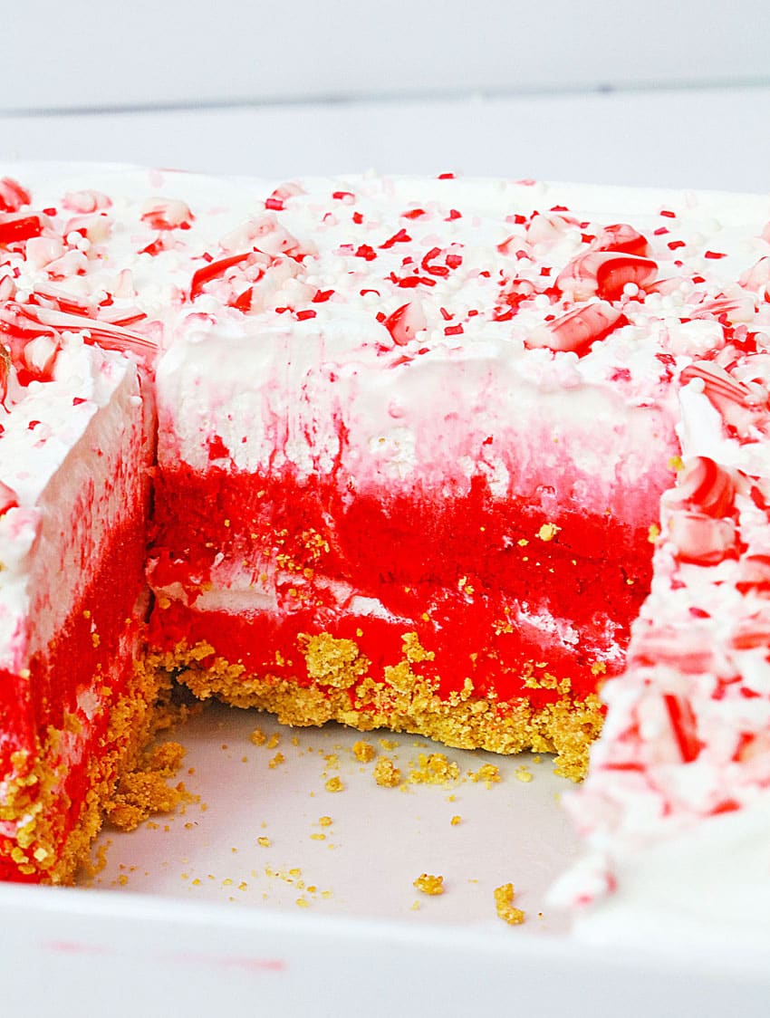 a close up of a candy cane lush dessert with a slice removed to show the layers