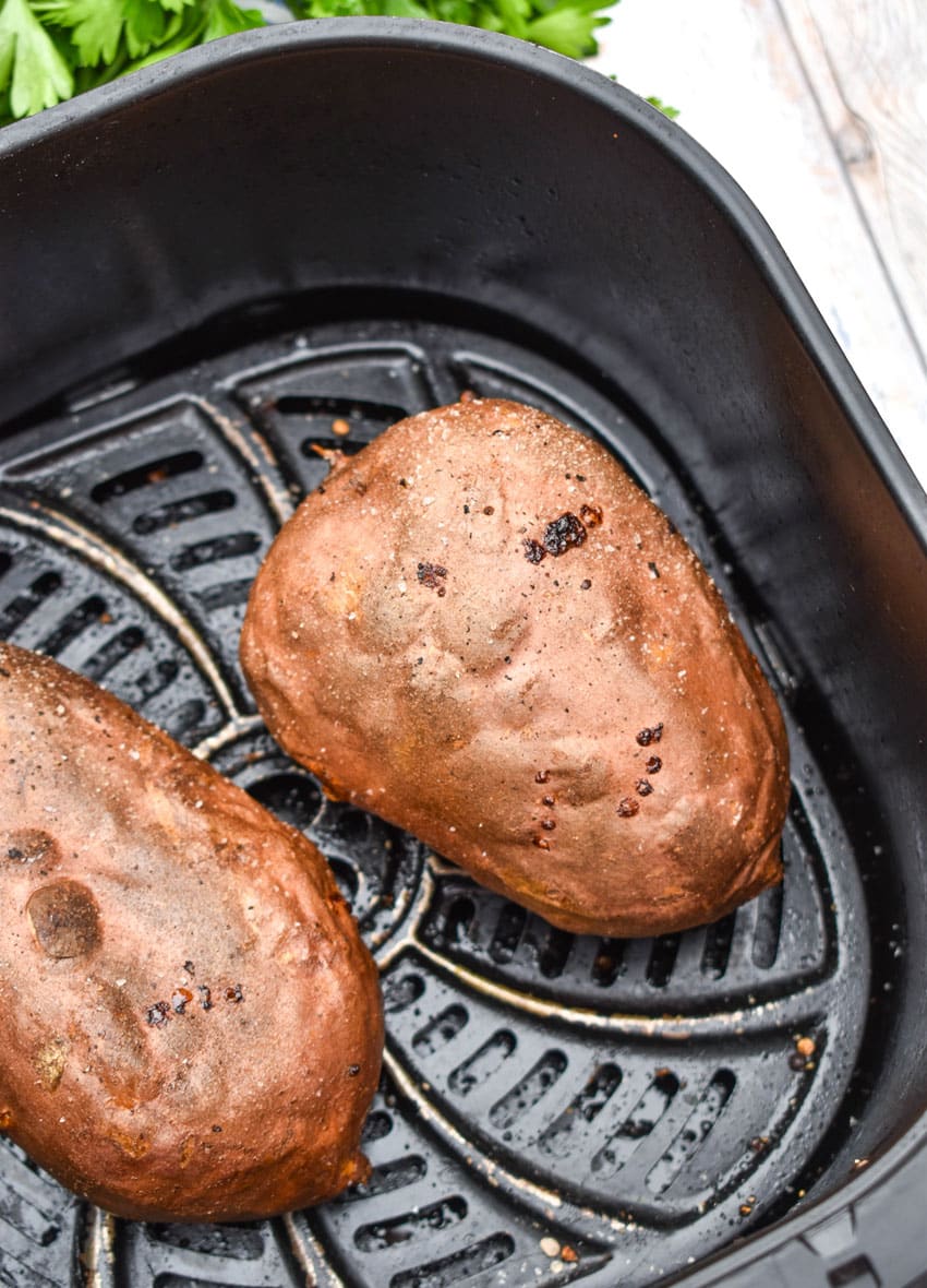 baked sweet potatoes in the basket of an air fryer