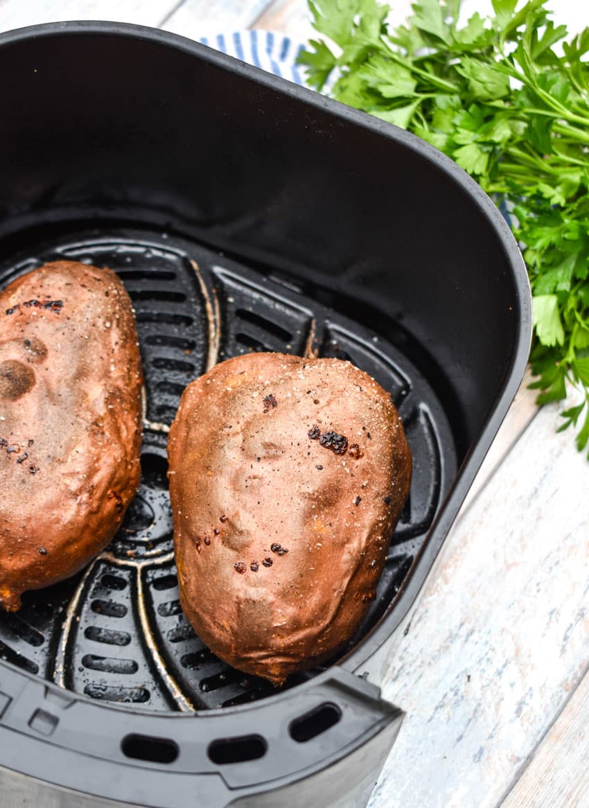 baked sweet potatoes in the basket of an air fryer