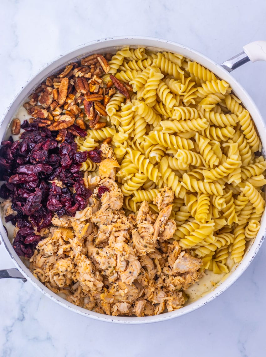 cranberry white cheddar chicken pasta ingredients in a large white skillet