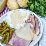 easy ham gravy shown over slices of spiral ham on a white dinner plate