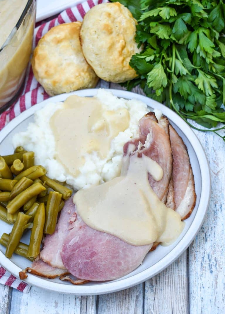 easy ham gravy shown over slices of spiral ham on a white dinner plate