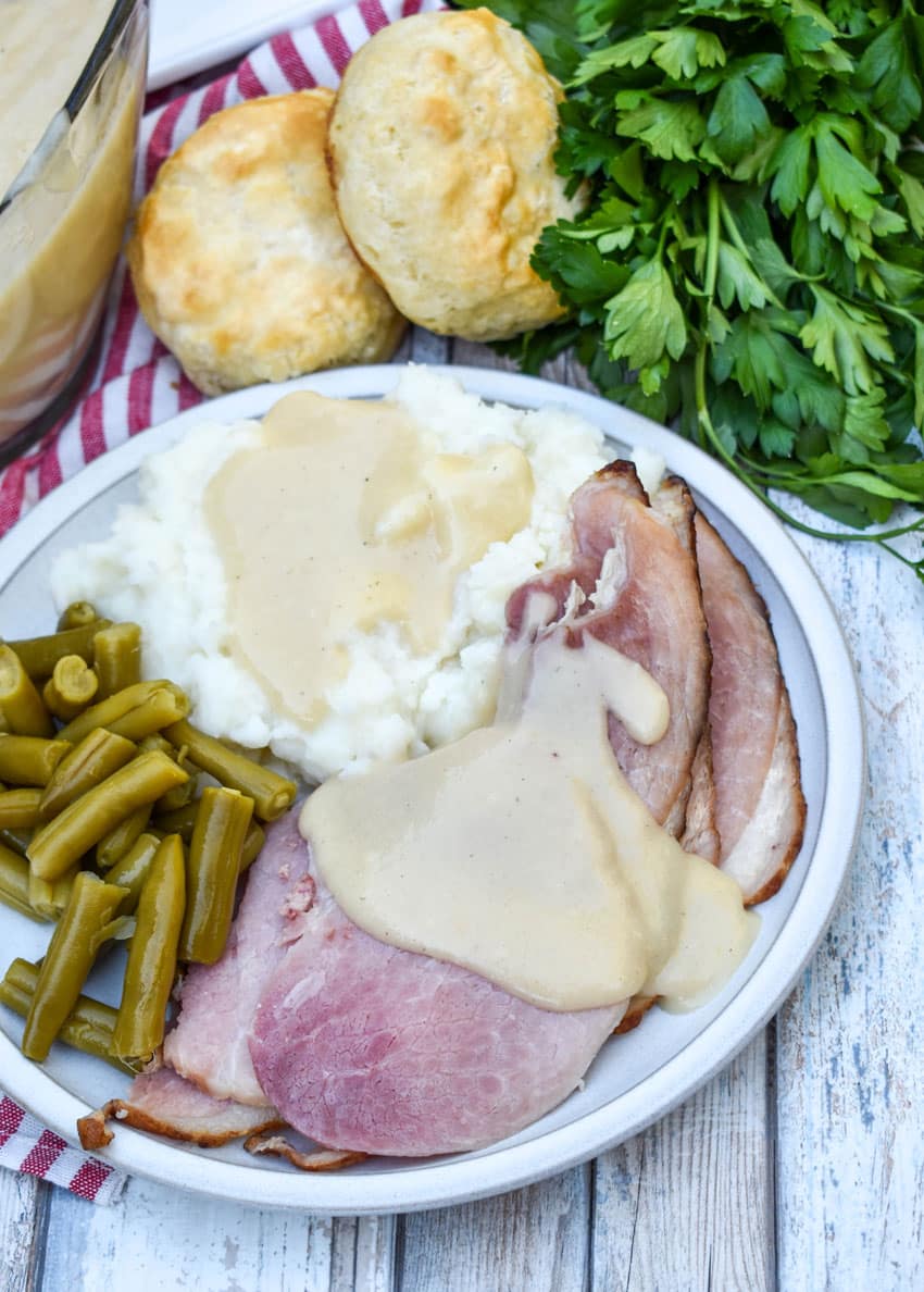 easy ham gravy shown over slices of spiral ham on a white dinner plate