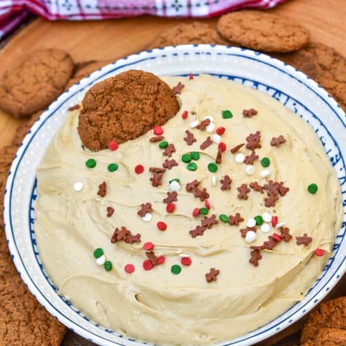 gingerbread cheesecake dip in a white bowl surrounded by gingersnap cookies