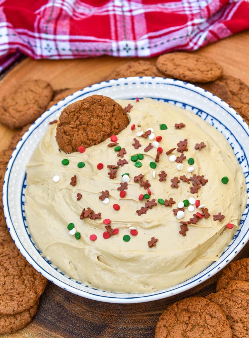 gingerbread cheesecake dip in a white bowl surrounded by gingersnap cookies