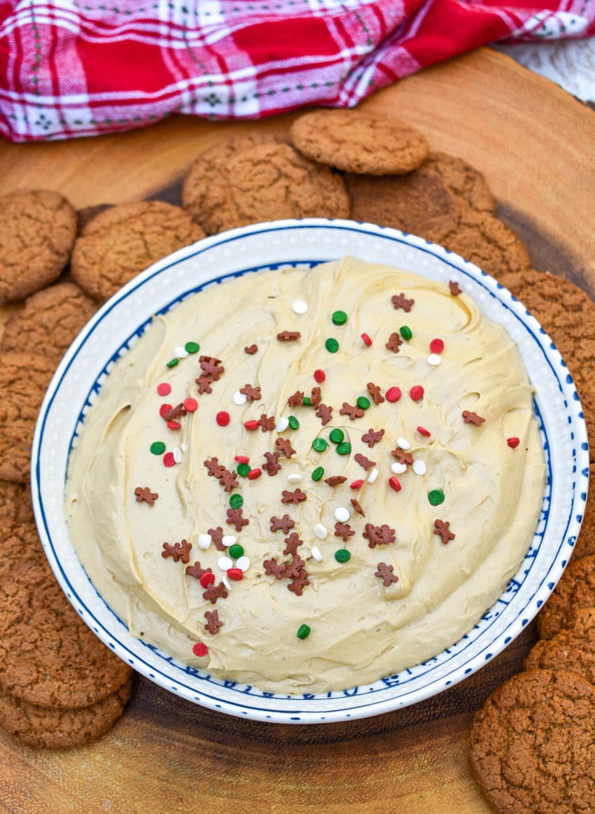 gingerbread cheesecake dip in a white bowl surrounded by gingersnap cookies