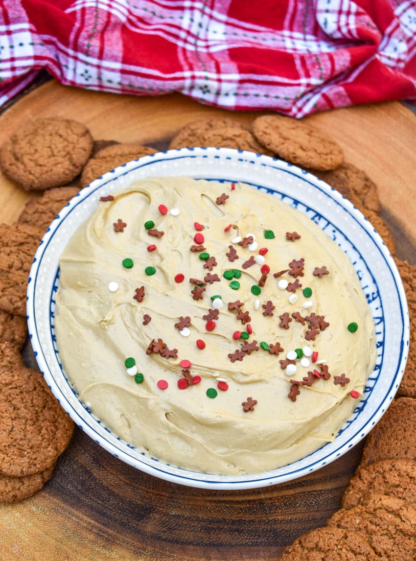 gingerbread cheesecake dip in a white bowl surrounded by gingersnap cookies