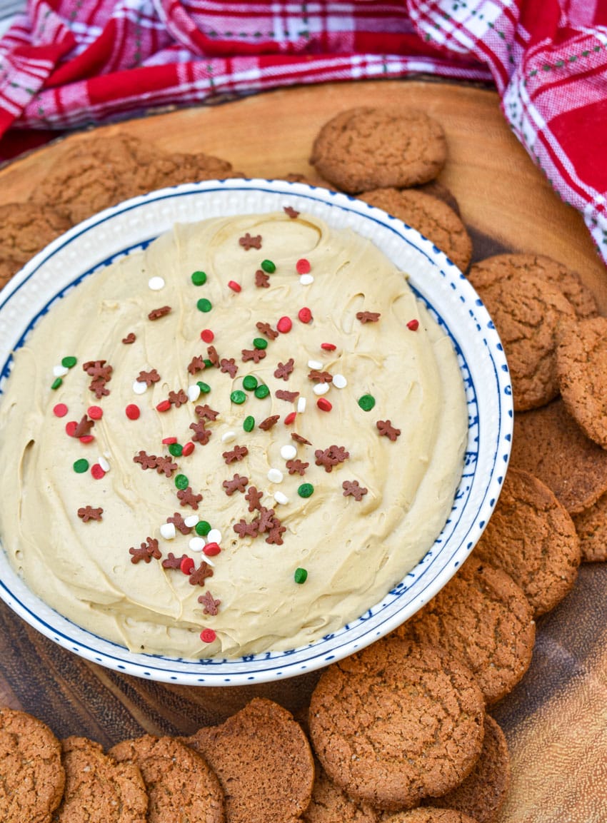 gingerbread cheesecake dip in a white bowl surrounded by gingersnap cookies