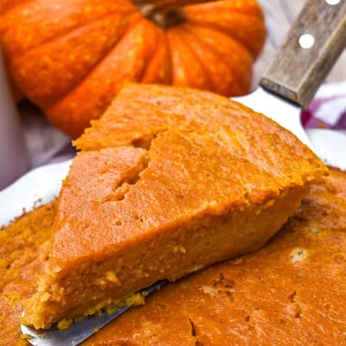 a wooden pie server holding up a slice of impossible pumpkin pie