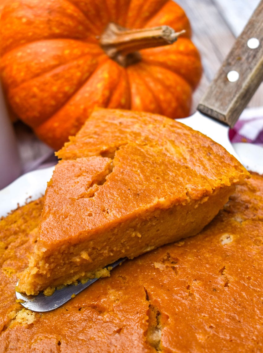 a wooden pie server holding up a slice of impossible pumpkin pie