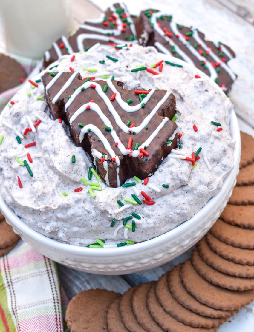 Chocolate Little Debbie Christmas Tree Cake dip in a white bowl topped with festive sprinkles and a dessert cake in the center