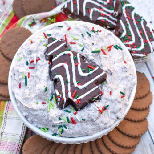Chocolate Little Debbie Christmas Tree Cake dip in a white bowl topped with festive sprinkles and a dessert cake in the center