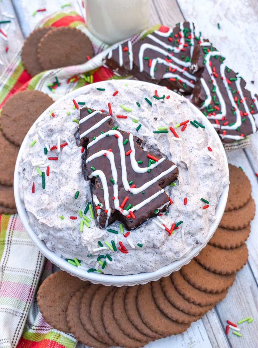 Chocolate Little Debbie Christmas Tree Cake dip in a white bowl topped with festive sprinkles and a dessert cake in the center