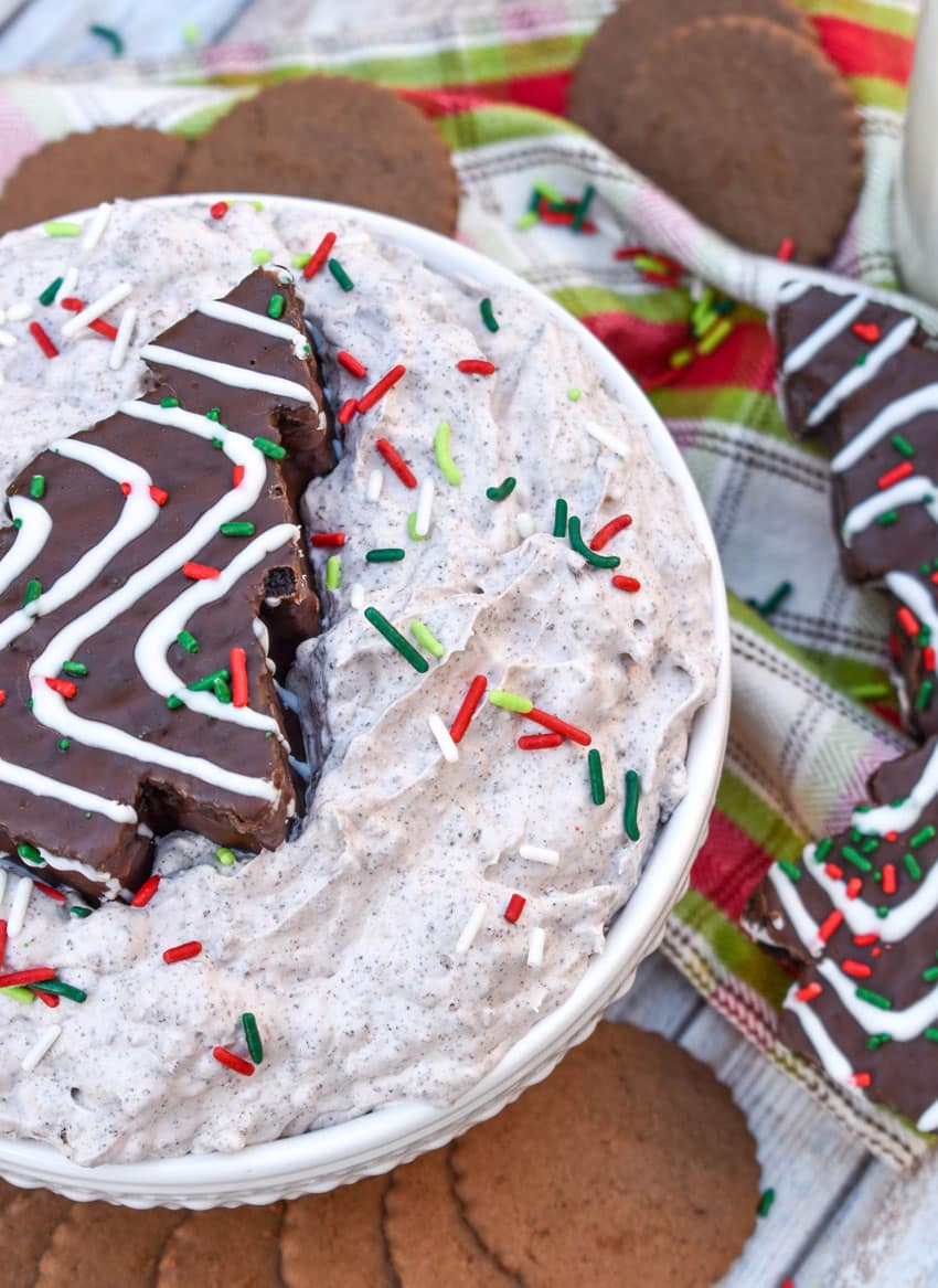 Chocolate Little Debbie Christmas Tree Cake dip in a white bowl topped with festive sprinkles and a dessert cake in the center