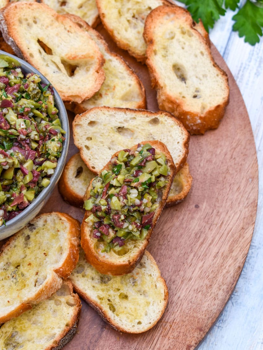 olive tapenade on a homemade crostini on a wooden serving board