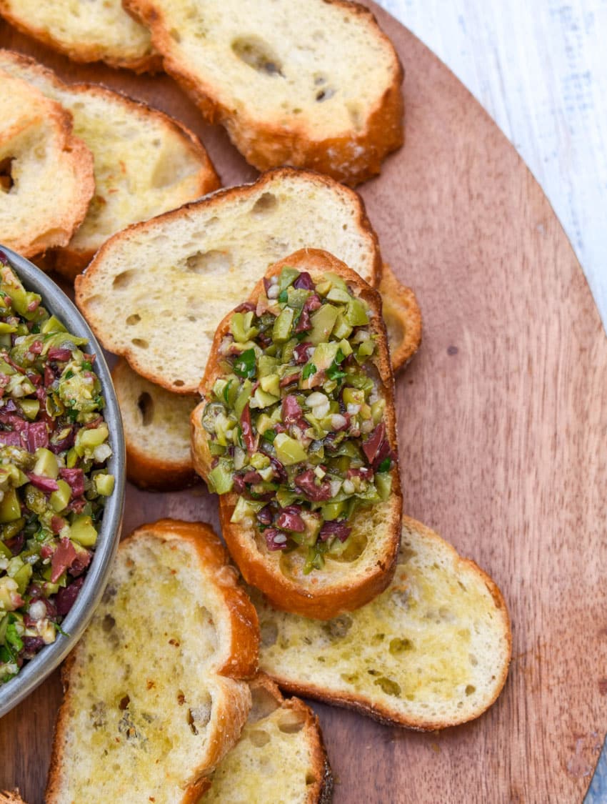 olive tapenade on a homemade crostini on a wooden serving board