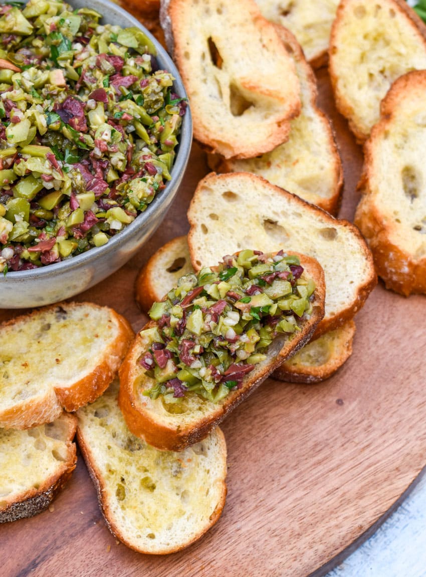 olive tapenade on a homemade crostini on a wooden serving board