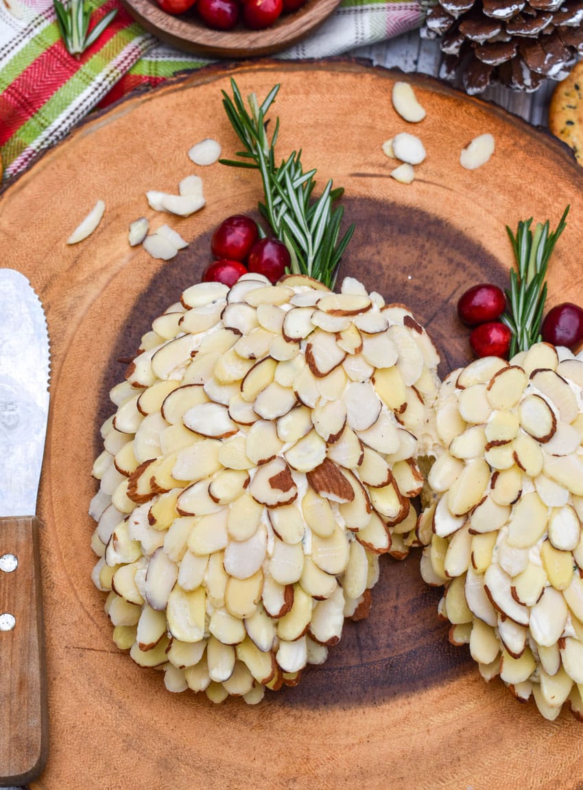 pinecone holiday cheese balls on a wooden serving board