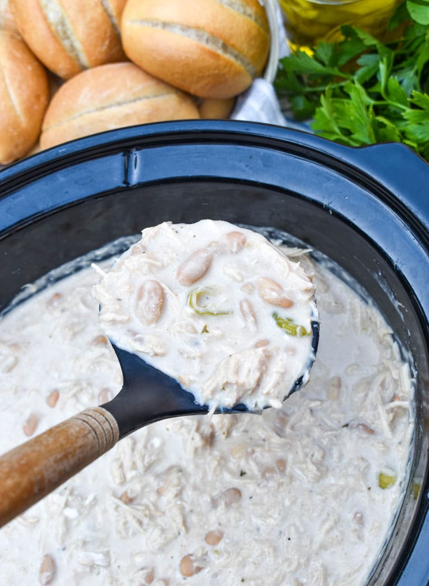 a wooden handled ladle holding up a scoop of creamy mississippi chicken chili