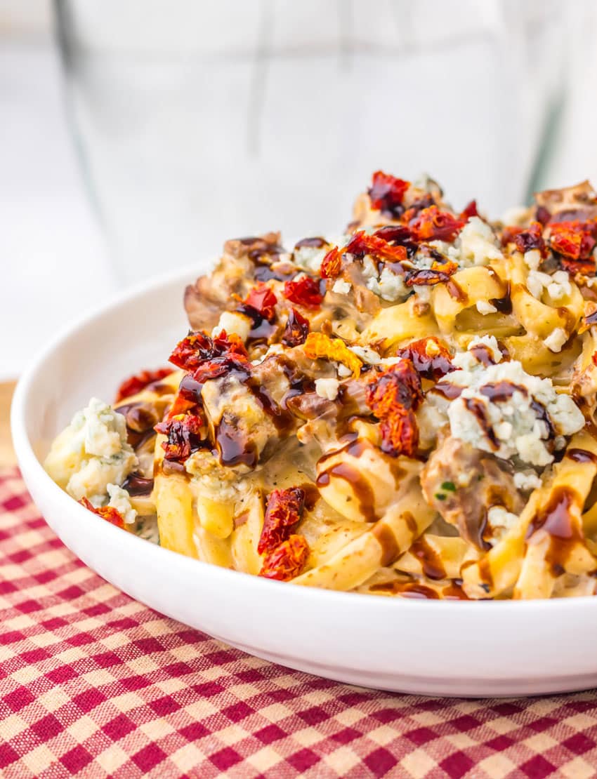 a close up of homemade steak gorgonzola pasta in a shallow white bowl