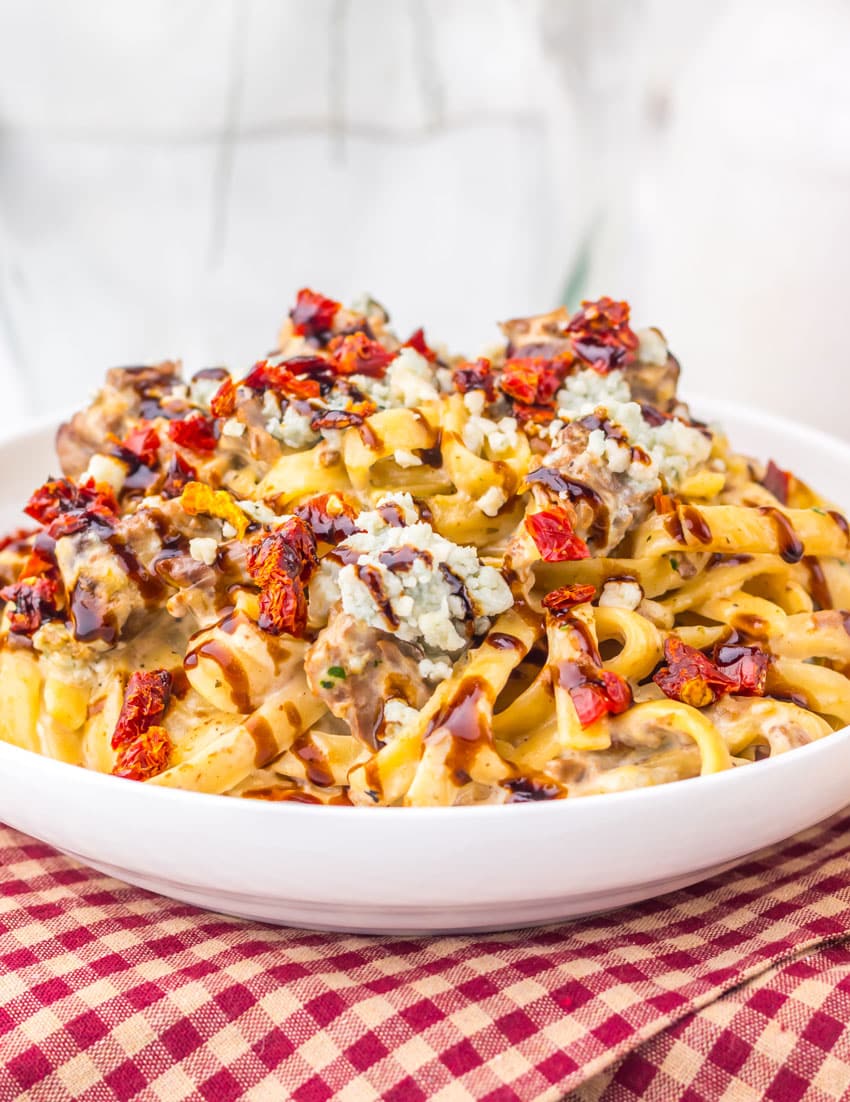 a close up of homemade steak gorgonzola pasta in a shallow white bowl