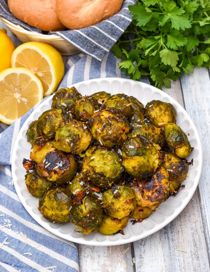 smashed brussels sprouts topped with shredded parmesan cheese on a small white plate