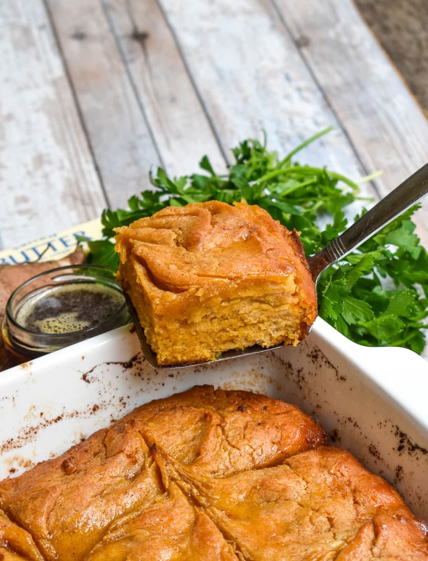a sweet potato butter swim biscuit resting on the edge of a white baking dish
