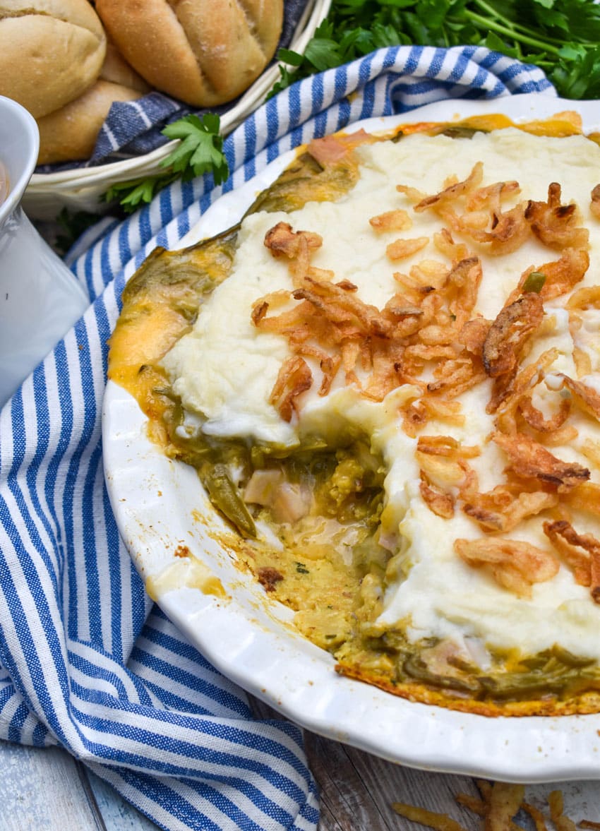 a wooden spoon scooping thanksgiving leftover pot pie out of a white pie dish