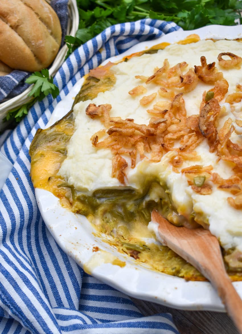 a wooden spoon scooping thanksgiving leftover pot pie out of a white pie dish